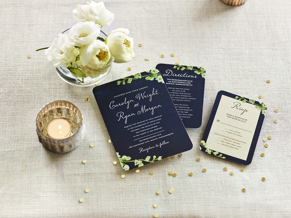 A photograph of a wedding invitation, directions card, and an RSVP card.